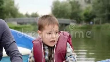 可爱的小孩在湖上对着镜头说话和微笑。 可爱的孩子在公园的木船上航行。 可爱的小男孩